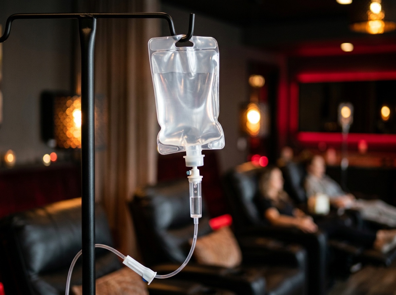 Clear IV fluid bag dripping on an IV pole in a clinic lounge Clear IV fluid bag dripping on an IV pole in a clinic lounge