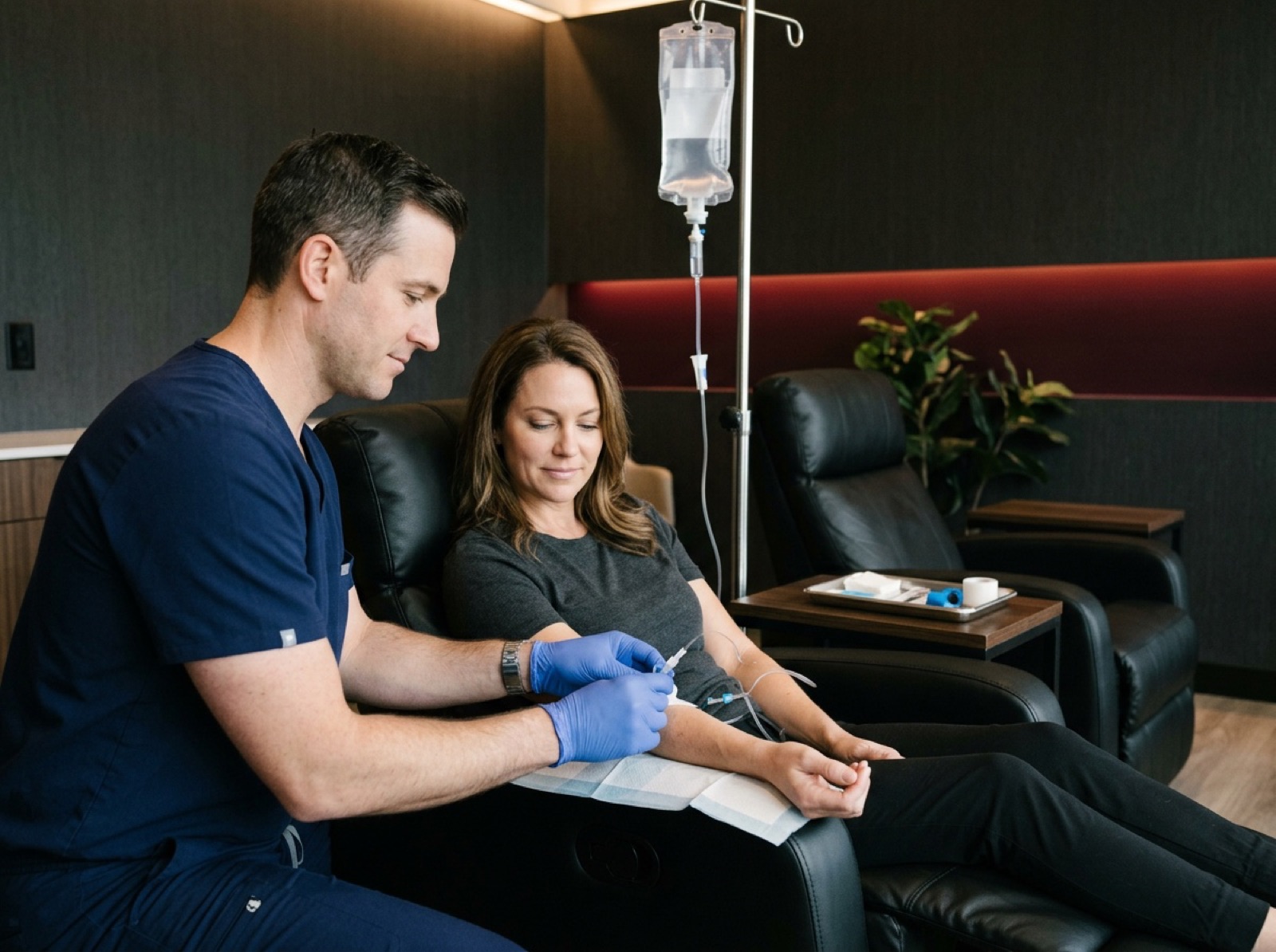 Provider in scrubs placing an IV line in a patient’s arm before an IV drip Provider in scrubs placing an IV line in a patient’s arm before an IV drip